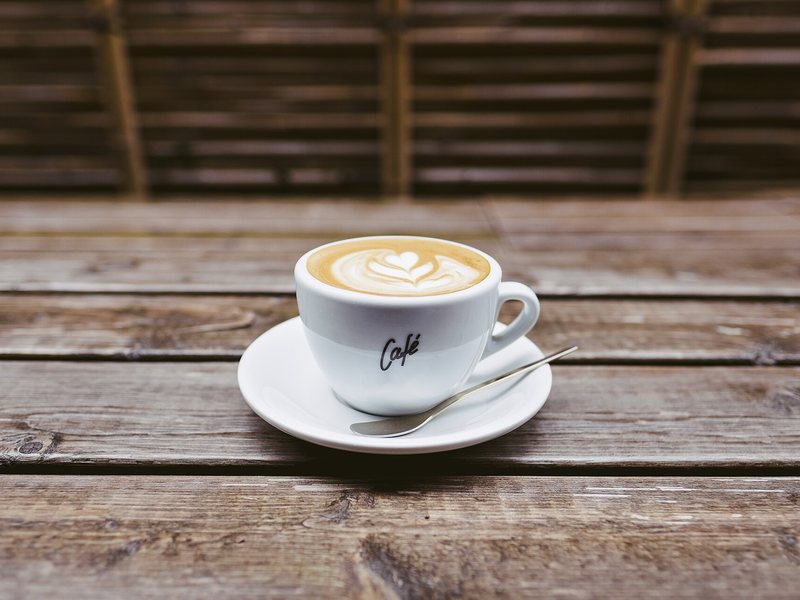 Cangkir kopi dengan latte art di meja kayu