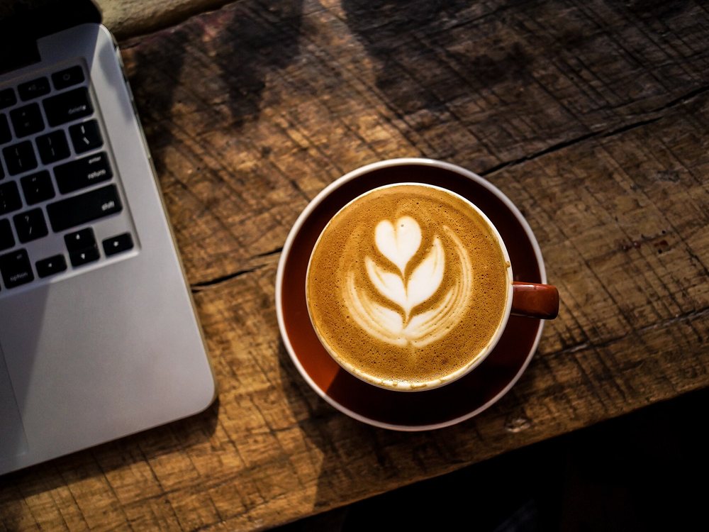 Secangkir kopi dengan latte art di atas meja kayu